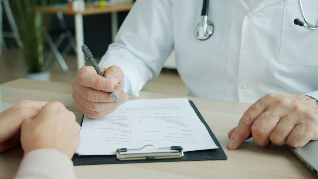 Doctor writing on patient chart during consultation
